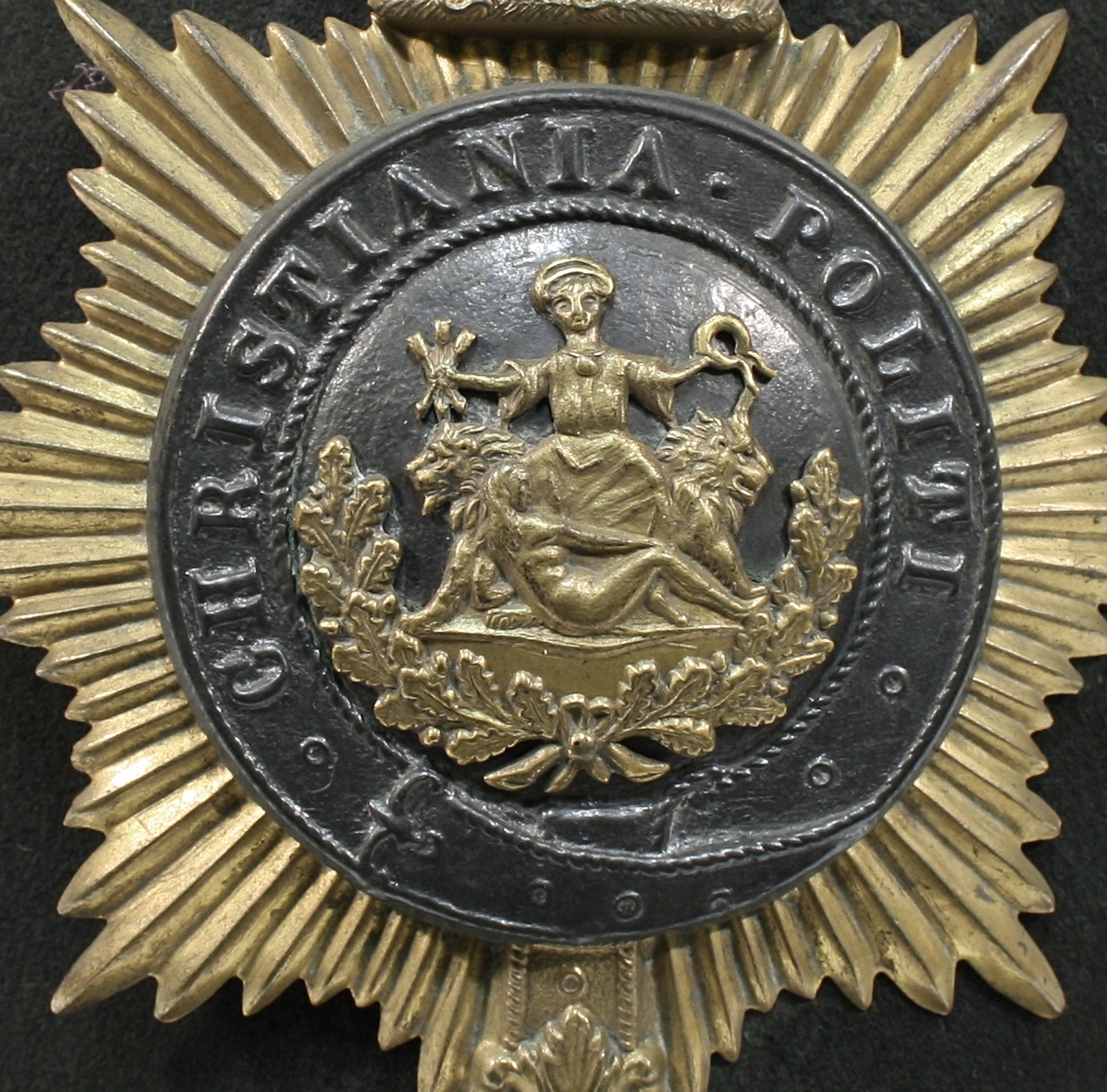Britiskinspirert hjelmform "Bobby typen". Foran er Oslos byvåpen omringet av belte og stjerne, med krone over. På toppen er en rose av metall.