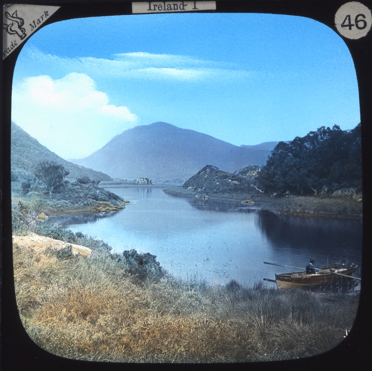 Kolorerade fotografier.
Topografisk vy från Irland, med båt i förgrunden. Ur bildserien "Irland I".