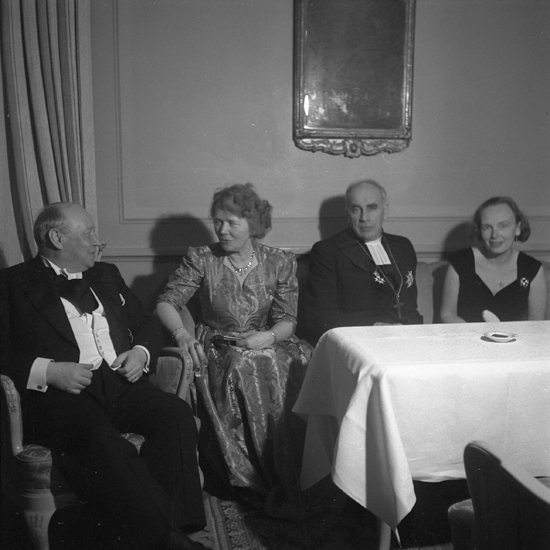 Landshövding Thorwald Bergquist med fru som sitter och pratar med dåv. biskop Yngve Brilioth med fru, på avskedsfesten
på Stadshotellet, Växjö 1950.