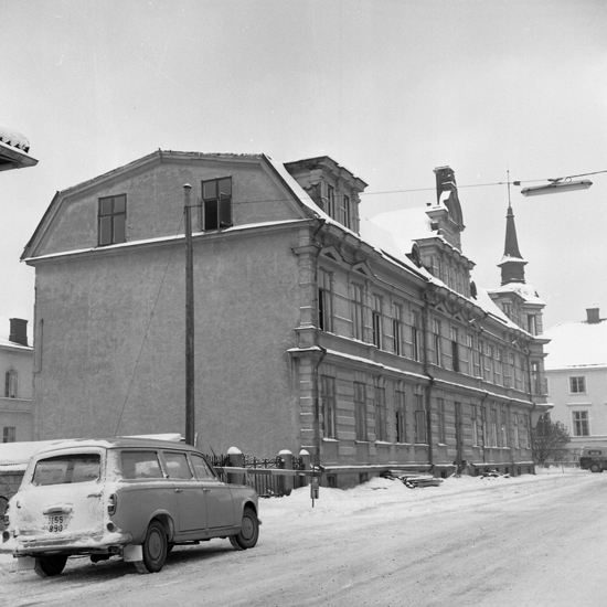 Foto av rivningsfastighet på Kronobergsgatan, Växjö. 
I bakgrunden skymtar församlingshemmet (von Baumgartenska gården). 
(Vinterbild).
