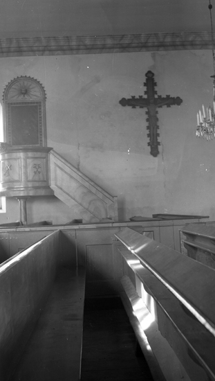 Foto av en predikstol med ett krucifix på väggen.