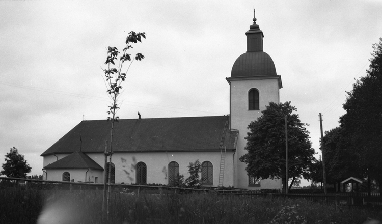 Foto på en kyrka med en mur utanför.