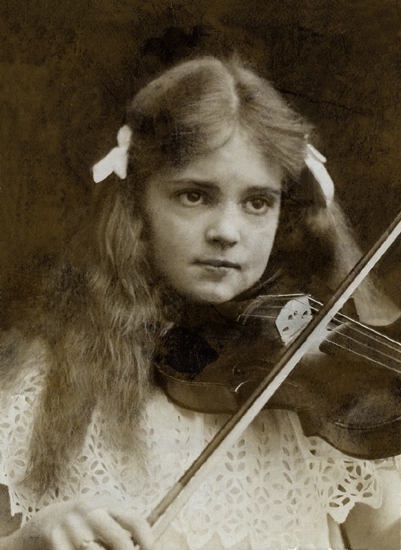 Porträtt (bröstbild, halvprofil) av en flicka i vit spetsklänning, med
rosetter i håret.
Hon har en fiol under hakan som hon spelar på. 

Hilla-Brita Trolle (1894-1943), dotter till  friherre Nils Trolle (1859-1930) 
och  h.h. Anna, f. Leijonhuvud (1869-1957), Trollenäs, Eslöv.
Hilla-Brita Tr. gifte sig 1:o 1915 m. baron Hans von Blixen-Finecke 
(1886-1917) och 2:o 1921 med greve Carl Axel Trolle-Wachtmeister (1893-1956), Trolle-Ljungby.
Källa: Svensk Adelskalender 1904, 1916,1936, 1949. Elgenstierna, Gustaf, "Svenska Adelns Ättartavlor".