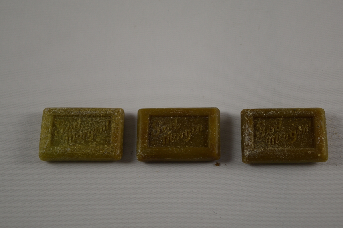 Rektangulær såpe, grønn, tre like såper (A, B, C) produsert på Saanums Sepefabrikk i Mandal. Rektangulær fordypning med relieffteksten "God morgen!" på overside og "Saanum Mandal" på underside.