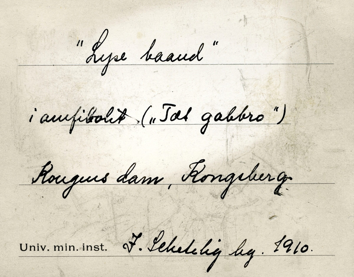 To etiketter i eske:

Etikett 1:
«Lyse baand»
i amfibolit («Tæt gabbro»)
Kongens dam, Kongsberg
J. Schetelig leg. 1910.

Etikett 2:
«Lyse baand»
i amfibolit («Tæt gabbro»)
Kongens dam, Kongsberg
J. Sch leg. 1910.