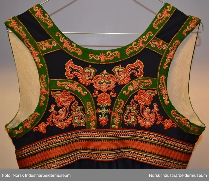 Livet er foret med et ubleket stoff. Livet er mørkt blått med grønn kanting. Både kantene og livet er prydet med plattsøm foran og bak. 
Nederst på stakken er det to border. Den øverste er  i grønt kantet med lilla og orange kontursting. Den nederste er i rødt kantet med gult. Nedenfor bordene ses den mørkeblå stakken. Den er kantet med rødt. 
Det brikkevevde beltet som hører til bunaden er sydd fast i kanten på livet. Borden i midten er orange og svart. På hver ytterside er det en rød, hvit og svart bord. Beltet har også striper i brunt, hvitt, rødt, svart og turkis. Beltet lukkes med hekter. Begge frynseendene på beltet er klipt av. Det ene frynesstykket er montert på beltet, slik at det alltid henger ned langs stakken i samme lengde. Det andre frynsestykket er løst og må festet på beltet med en sikkerhetsnæl eller liknende.