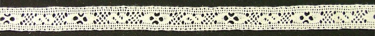 Längd: 241 cm. Bredd: 1,3 cm
2 tr blekt vitt lingarn. Skånsk knyppling utförd med dubbelslag, fläta och vävbotten. Mönstret bildar s-formiga vävbottnar omväxlande med ovala vävbottnar med kryss av flätor i mitten. Galler i stadkanterna.

Enligt G. Ingers, "Skånsk knyppling", 1966 heter mönstret "Ess och kringlor"
Inger Danielsson sept 1981.

Tidigare katalogisering enl uppgift av Elisabeth Thorman:
Mellanspets, 240 x 1. Blekt tråd.