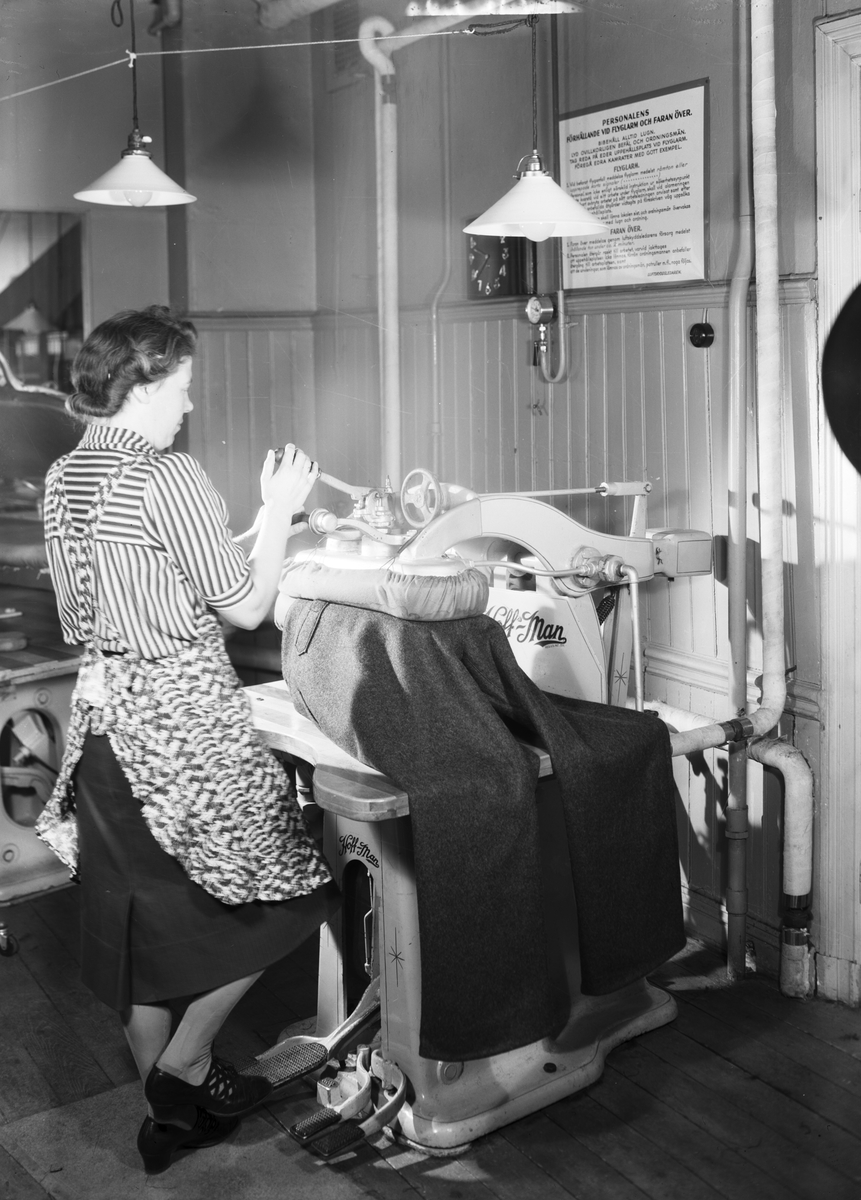 J. F. Bellanders AB. Pressning av byxor,ev uniformsbyxor. Det är krigstid syns på anslaget på väggen. Bellanderbolagen startades av J. F. Bellander. Från 1920 i fabriksmässig omfattning.Deras mest kända varumärke är Björnkläder.