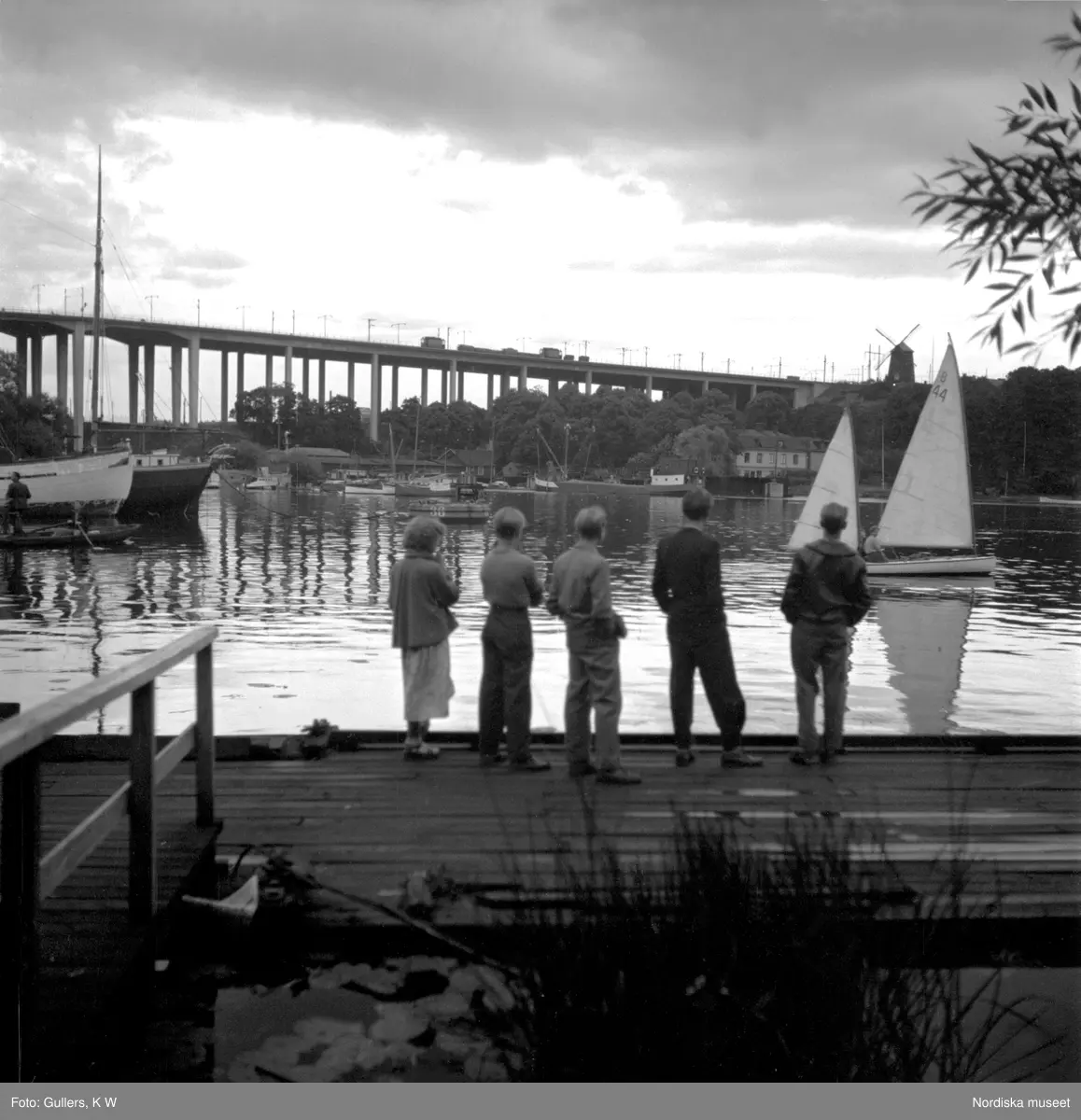 Södermalm, Stockholm. En grupp pojkar betraktar båtar på vattnet. Skanstullsbron i bagrunden.