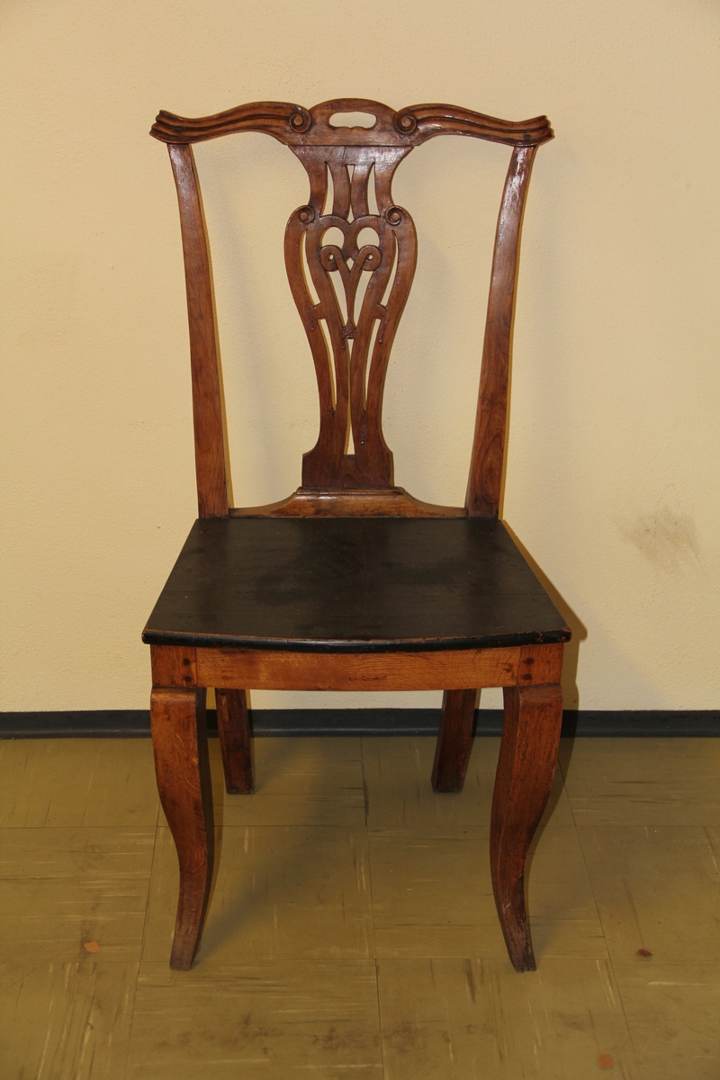 Chippendale-inspirert stol, brun med sort sete. Utskjæringer. Ryggbrettet dekorativt utformet, kinesisk-inspirerte "skuldre"