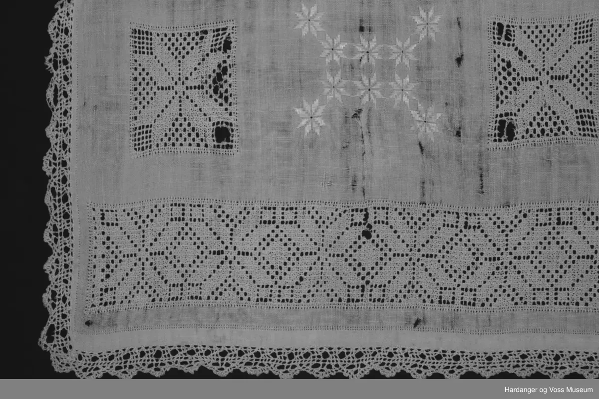 Over framstykket hekla blonde påsydd langs kanten, åttebladspirer