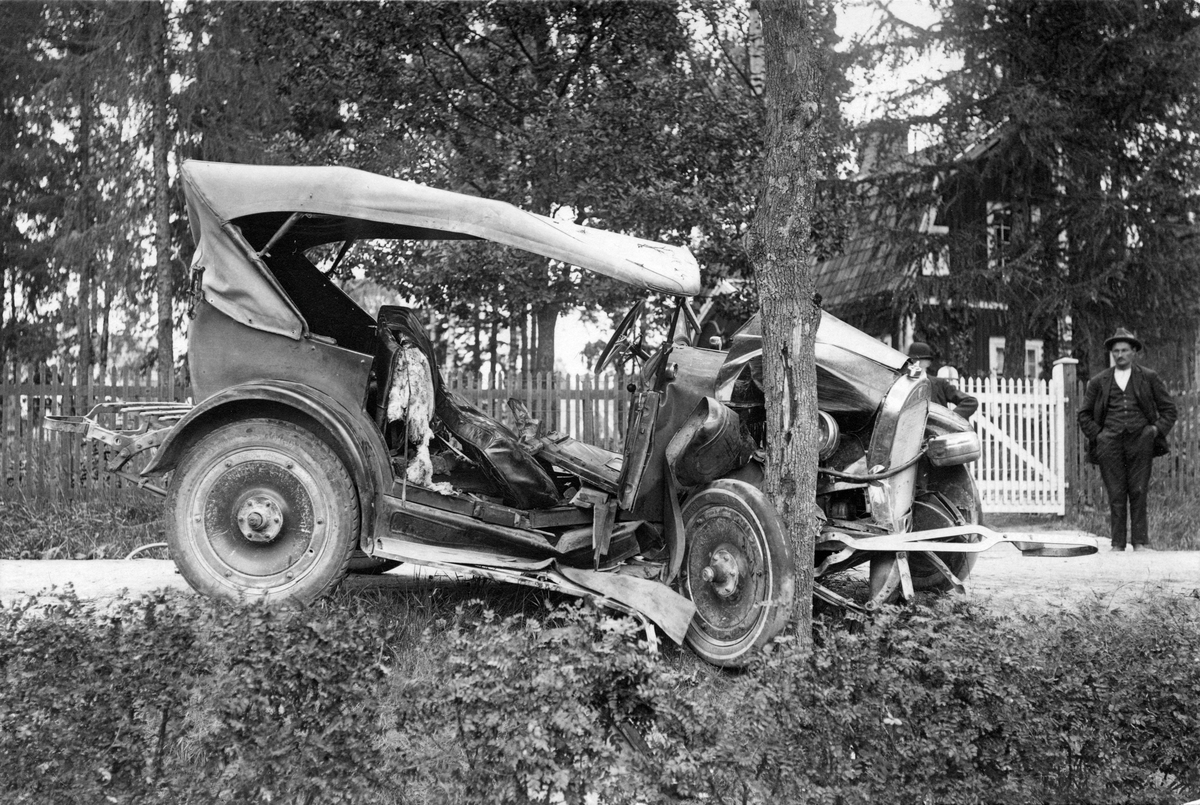 Äldre bil efter krock med träd vid pensionat, vid Folkets park, Köping,  lördagen 4 juli 1925.
 Oscar Gustavsson ("Kutis") var föraren.

(se även foton KM_82_6272 och KM_82_6698)