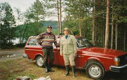 To menn står foran en rød Volvo stasjonsvogn. Turkledd. Fisk