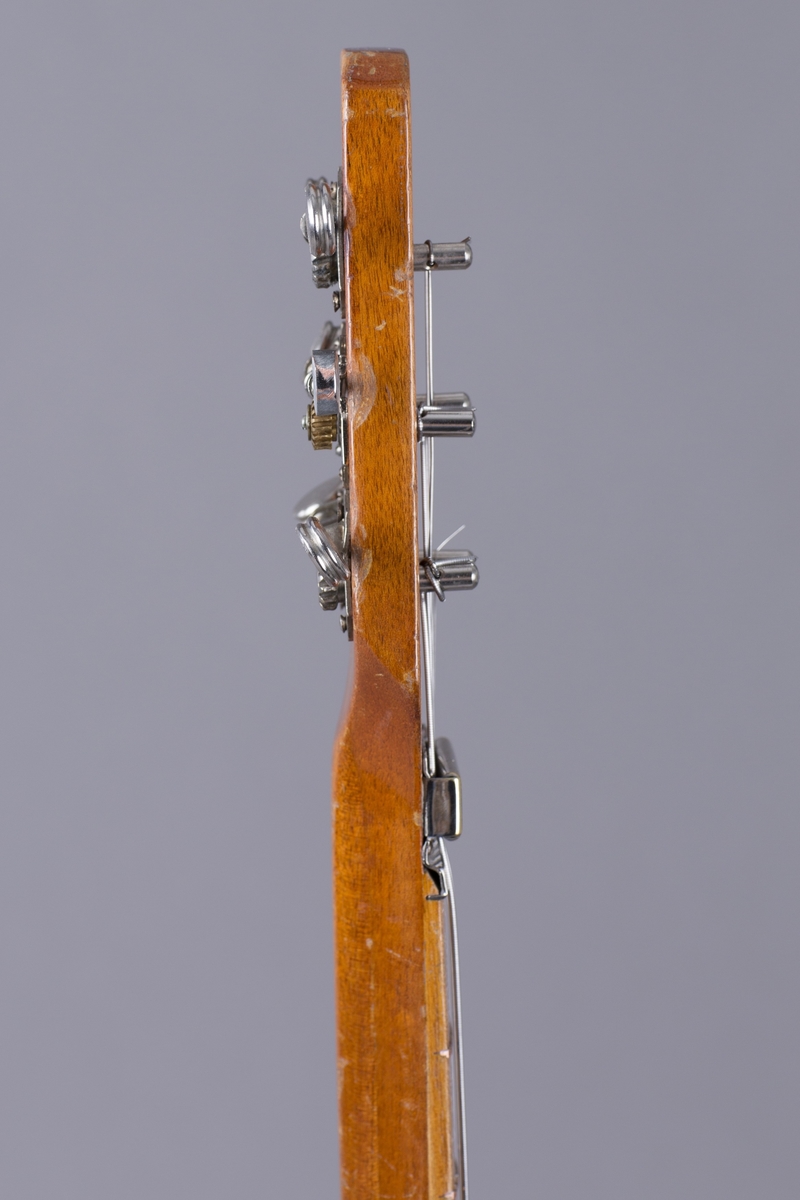 Elektrisk gitar med kropp og hals av mahogny. Magnet ved halsfeste og pickup ved strengefeste (NilsensSystem). Kontrollere for tilpasning og klangfarge. Tilpasning tilsvarer volum og gir størst volum på nivå 1. Enkelte av stemmeskruene er ikke originale.