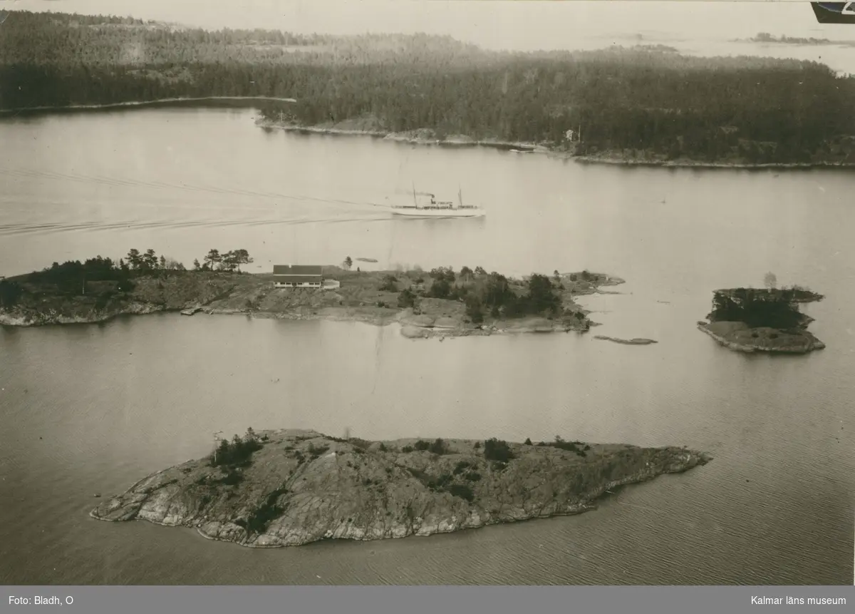 Flygfoto över ön Skansholmen vid farleden in till Västervik. Huset på ön är klubbhus för WSS (Westerviks SegelSällskap). Klubbhuset byggdes 1916 efter ritningar av arkitekt Axel J Sjögren.