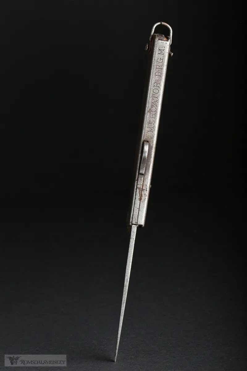 Foldbar tyskprodusert lommekniv. Kniven har to rom, et for hovedknivbladet, og et for en syl og en boksåpner. En liten hempe i metall er naglet fast i bakkant av kniven.