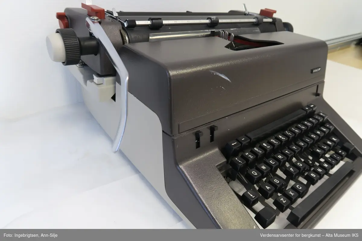 Skrivemaskin av mer moderne type. Transparent plasttrekk følger med.
