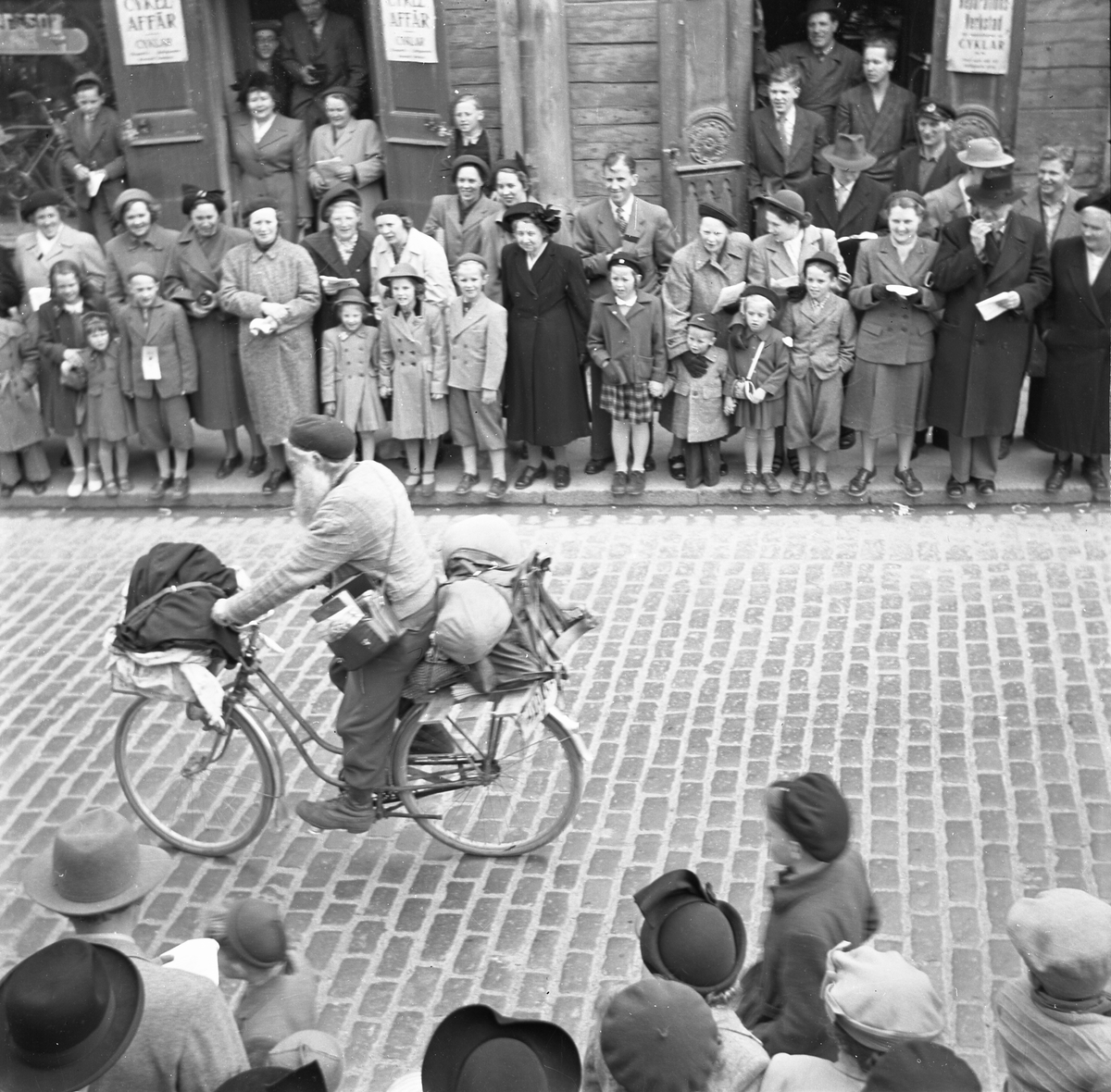 Orig. text: Majkarnevalen 1951.

Majgubbe på cykel, på Storgatan.