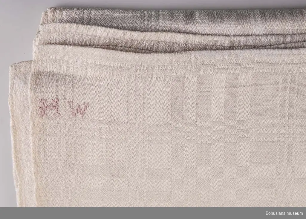 Bordsduk av linne i drällmönster. Märkt med korsstygn "H W", Helena Waldenström. Duken är hemvävd med söm i mitten.
Jämför mönster i duk UM000061