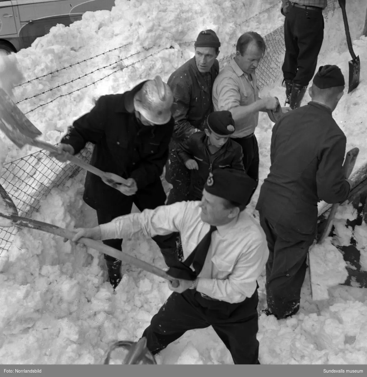 Tung blötsnö har rasat från Tennishallens tak i april 1959. Fyra lekande småpojkar hamnade under snön men tack vare en snabb insats av förbipasserande, personal från Bäckströms billackeringsfirma i grannfastigheten samt snabbt inkallat brandmanskap så grävdes pojkarna fram oskadda. På bild 2 ses längst fram brandmannen Algot Kamlind, i mitten av bilden en av de räddade pojkarna, tioårige Jan Granholm. Längst bak syns Idrottsparkens vaktmästare Norrbomsamt brandman Sven Nilsson. På bild 3 de framgrävda pojkarna Jan Granholm och Kent Sjödin,. åtta år, mannen mellan pojkarna är troligen Kents pappa Ivar Sjödin.