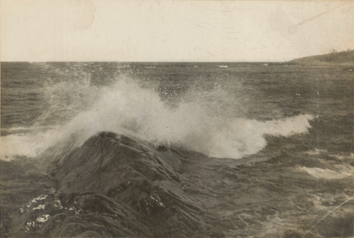 Naturbild på havet med kraftiga vågor som slår mot strandklippor.