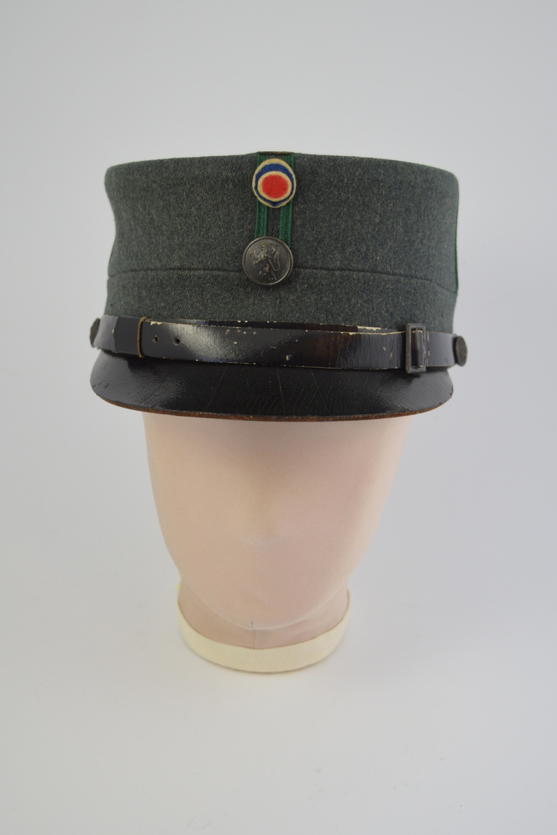 Uniform i tre deler: jakke, lue og patronveske. Innsvinget jakke med fire lommer,enkelt spent,nedbrettet krage. Bøtteformet lue med distinksjoner. Svart lærbrem og svart lærrem som går over bremmen. Kvadratisk patronveske i grønt lerretsstoff, med stor svar trykknapp foran.