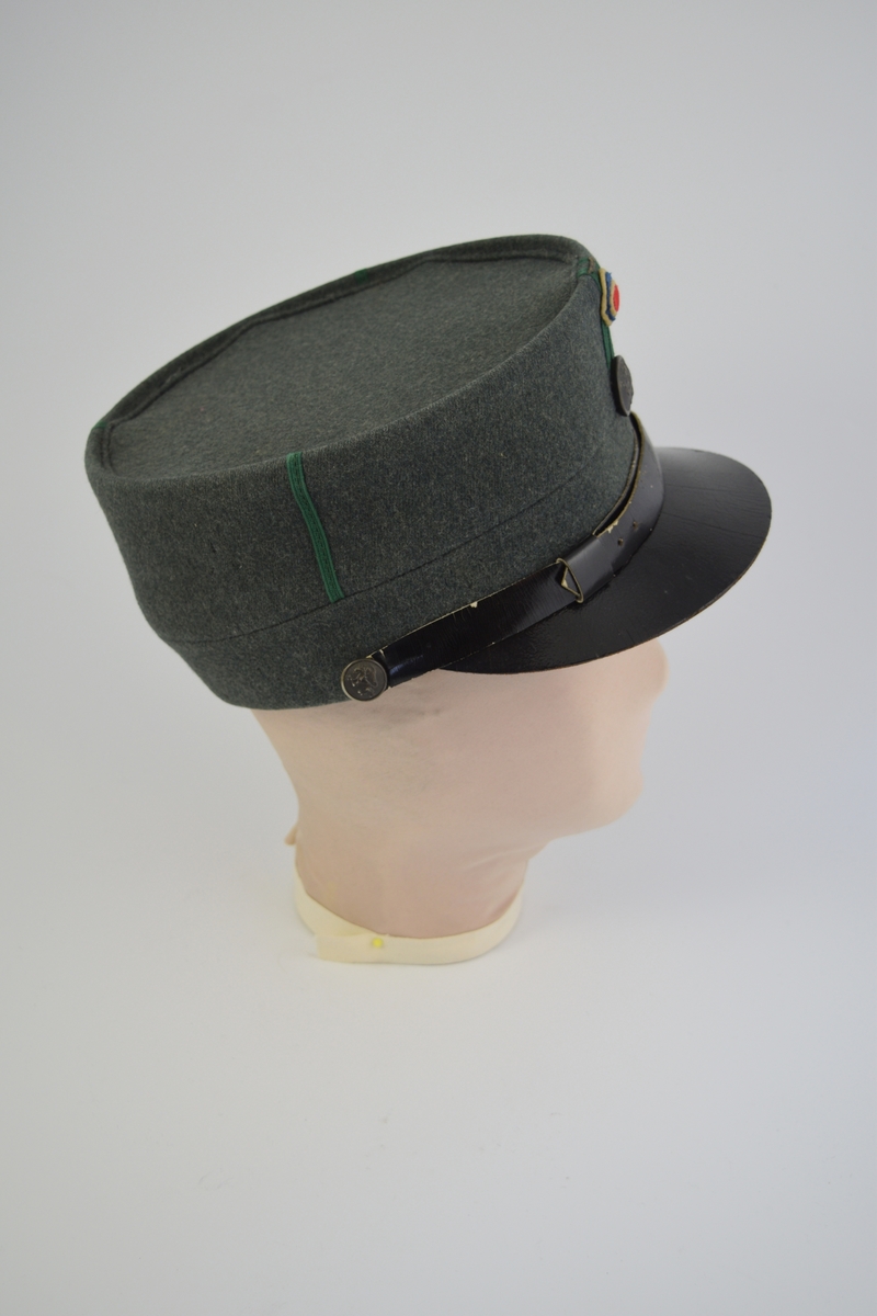 Uniform i tre deler: jakke, lue og patronveske. Innsvinget jakke med fire lommer,enkelt spent,nedbrettet krage. Bøtteformet lue med distinksjoner. Svart lærbrem og svart lærrem som går over bremmen. Kvadratisk patronveske i grønt lerretsstoff, med stor svar trykknapp foran.