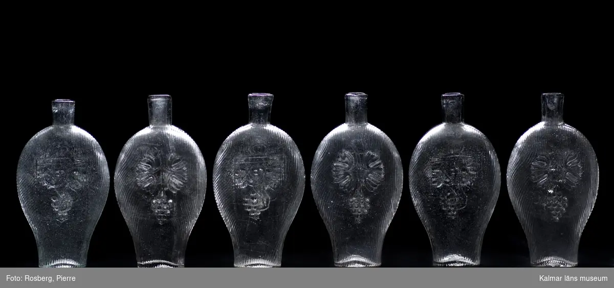 KLM 23287. Brännvinsflaskor av pressglas, 6 stycken. Av typen fickplunta. Höjden varierar något mellan 18,5 cm till 19,2 cm.