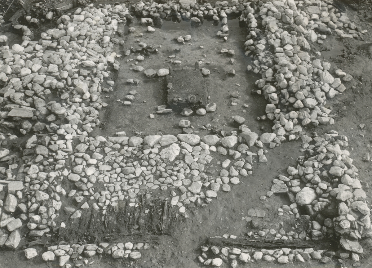Dokumentasjonsbilder i serie fra arkeologiske utgravingar av Borgundkaupangen. De forskjellige motiva viser ei årestove, brønn og ein kavleveg ved sida av ei rekke med påler.