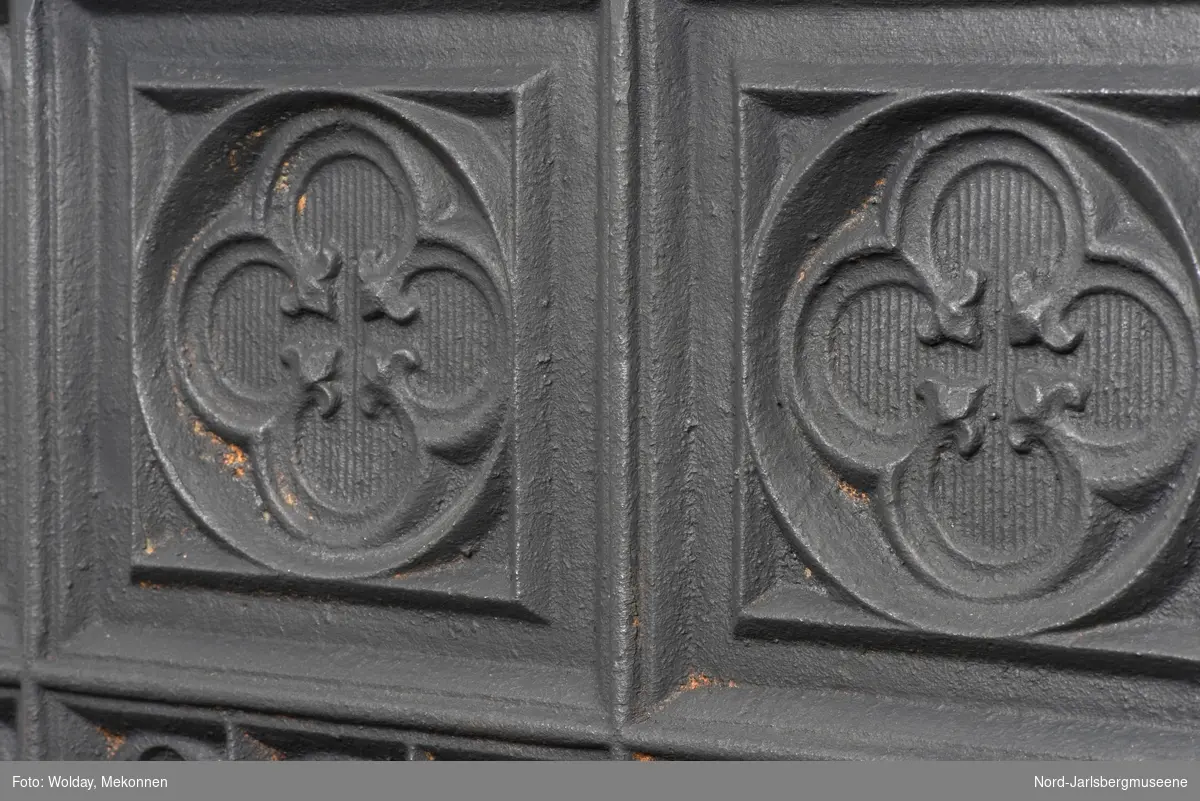 1.etasje (fyrrom), kortside frem: støpt dør med spiralhåndtak - døren løftes opp fra mottaker på platen, rund trekkluke til å snurre opp. Døren hengslet med  støpte bladelementer. Platen dekorert med hjørnerosetter og gotiske, retangulære , "trifolium"-buede relieff. Kortside bak: Inndelt i rektangulære felt med gotiske og klassisitiske elementer, med et kvadratisk midtfelt med en rund medaljong med en liten nisse/dverg med hakke. 1. et.langsider: inndelt i tre felt av gotiske elementer, det midterste feltet har en rund medaljong med en liten nisse/dverg med hakke. 2-4.etasje røykkamre: tverrgående kammer under sidekamrene. Under åpningene er tverrkamrene dekorert med to rosetter. Ellers er kammersidene dekket av stram geometrisk dekor. Åpningene mangler grinder unntatt en (øverst til høyre): grinden med nygotiske eementer, og en mytologisk kvinneskikkelse med septer, krone og...?.  Toppetasjen lav, som de tverrgående under. Toppsarg  med klassiske border. Mangler kronen (se katalog 1910)