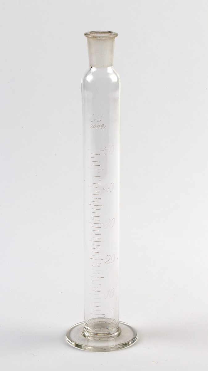 Målesylinder med innsnevret, slepen åpning øverst for propp (denne mangler). Utvidet rund fot . Gradert fra 10 - 50.