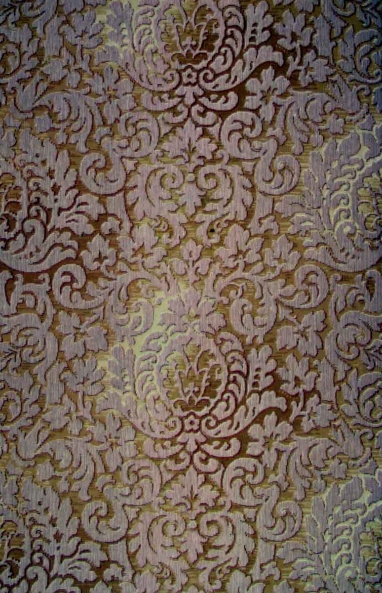 Ett ytfyllande silhuettmönster med franska liljan dekor i diagonalupprepning. Tryck i två beige nyanser på en melerad bakgrund i ljusbrunt samt i två nyanser senapsgult.