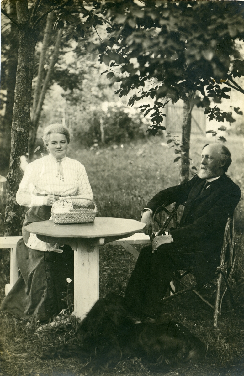Prost Thomas Barth og kona Maren Marie sitter ved et bord i prestegårdshagen.