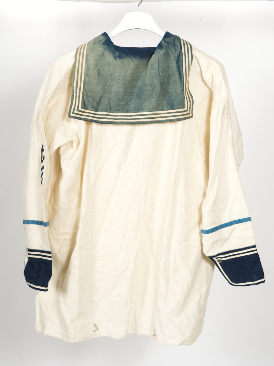 Blåkragad lärftesskjorta med blå ärmuppslag. Tre vita ränder på kragen samt två på uppslagen. Blått redgarnsband på ärmarna samt på den vänstra ankare och tre uppmuntringsvinklar av blått kläde.
Beklädnad till matros 1873.