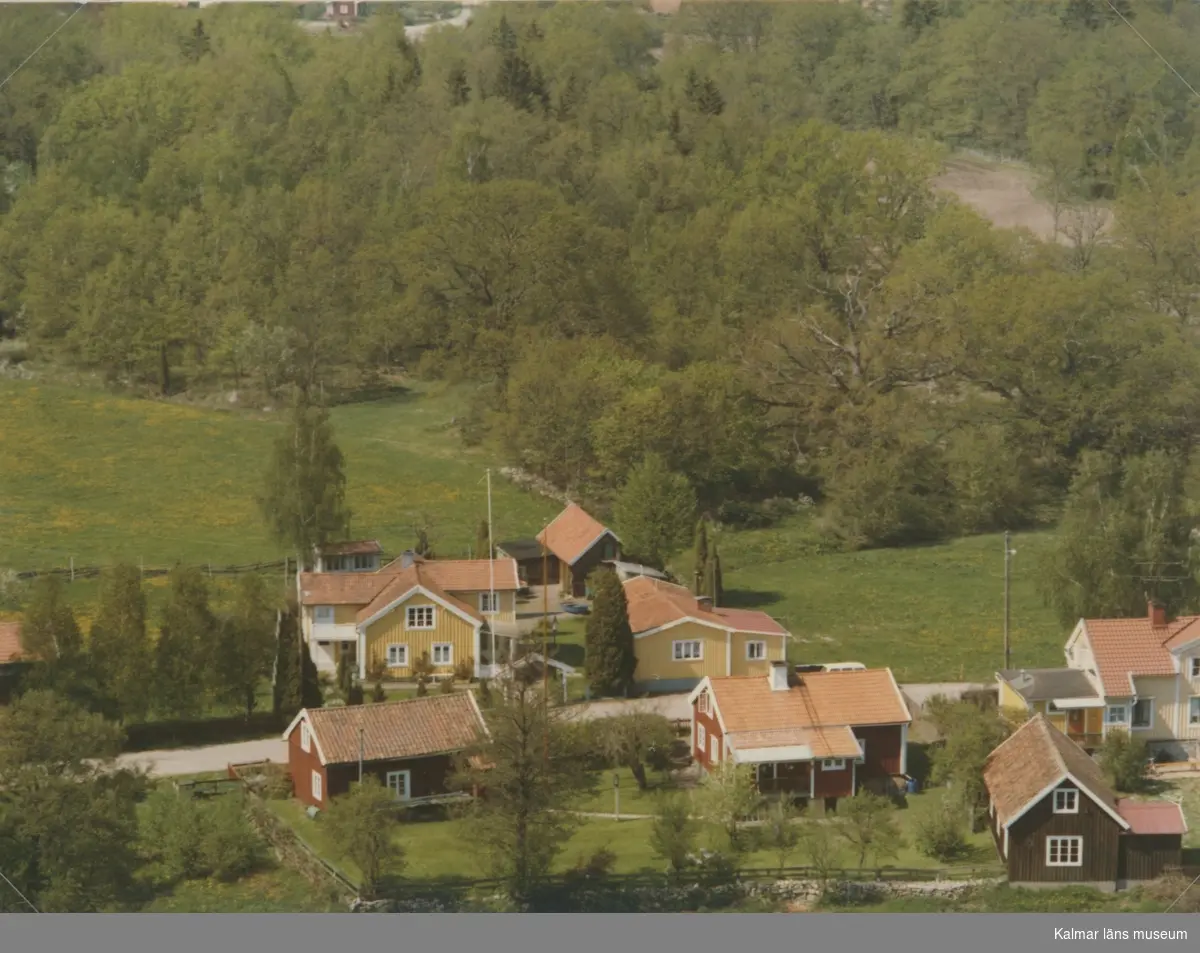 Flygfoto över Pataholm. Samhället med bostadshus och sidobyggnader samt äng.