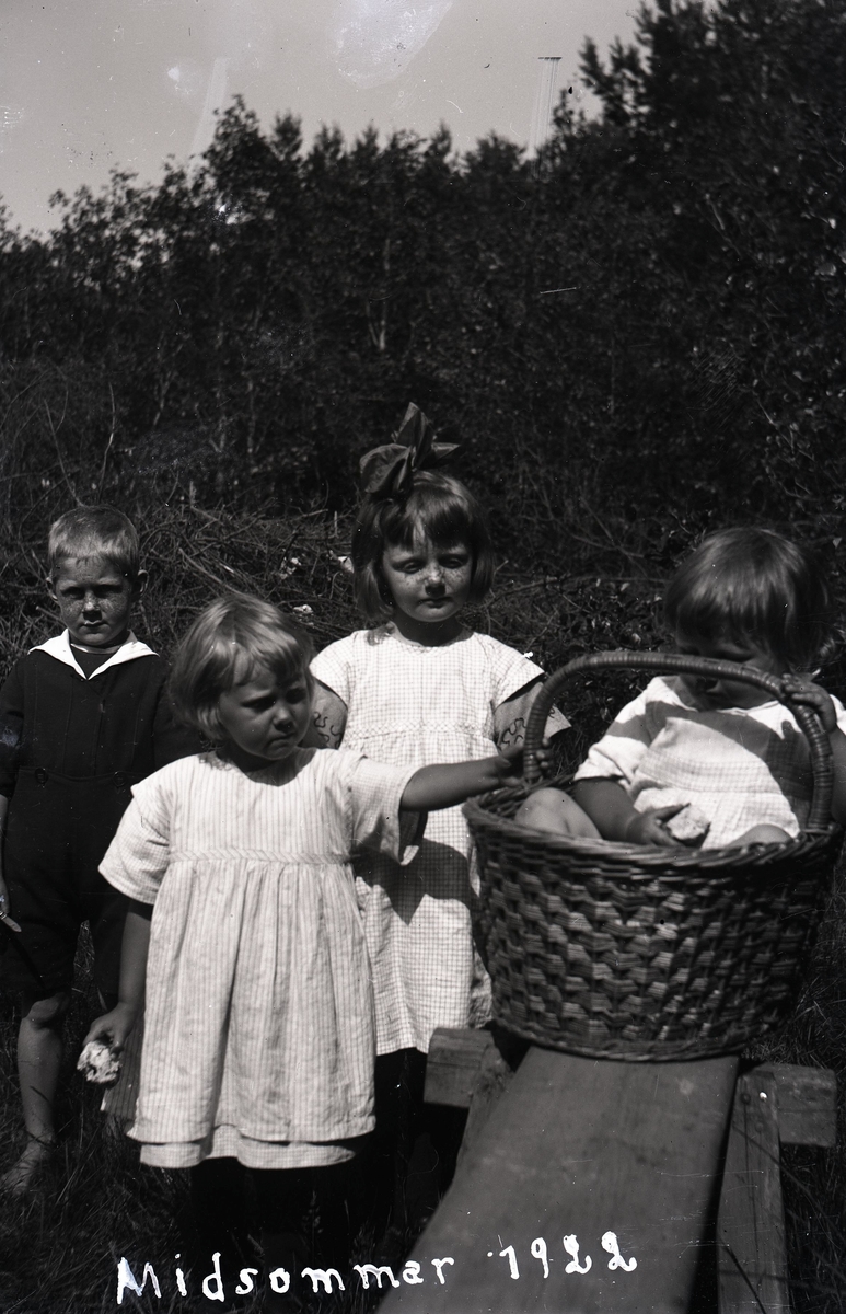 Barn varav en flicka i en korg på en träbänk.