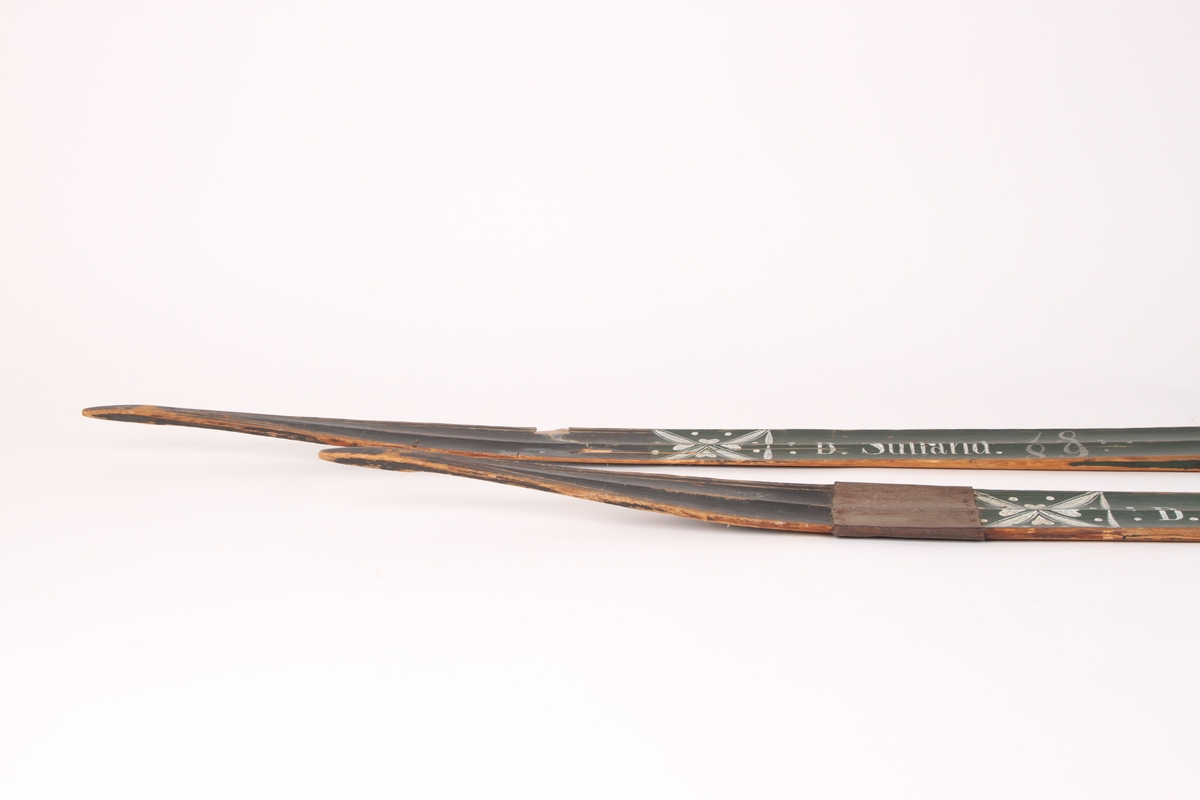 Et par treski i helved med lang og smal tupp, flat overside og fortykning under. Avsmalnende framski og jevnbred bakski og møneformet rygg langs hele skiens lengde. Dekoren er fra Krødsherad med fremre del av framskien malt i svart, og med rosett og navn med årstall i hvitt. Rosett også på skienes bakende. Skiene har tåstropp av vidje og har sannsynligvis hatt ilkebinding. Bindingshullene har innskjæring med skråsnitt på skienes sider. Skiene er rett avskåret bak. Ingen rand under.