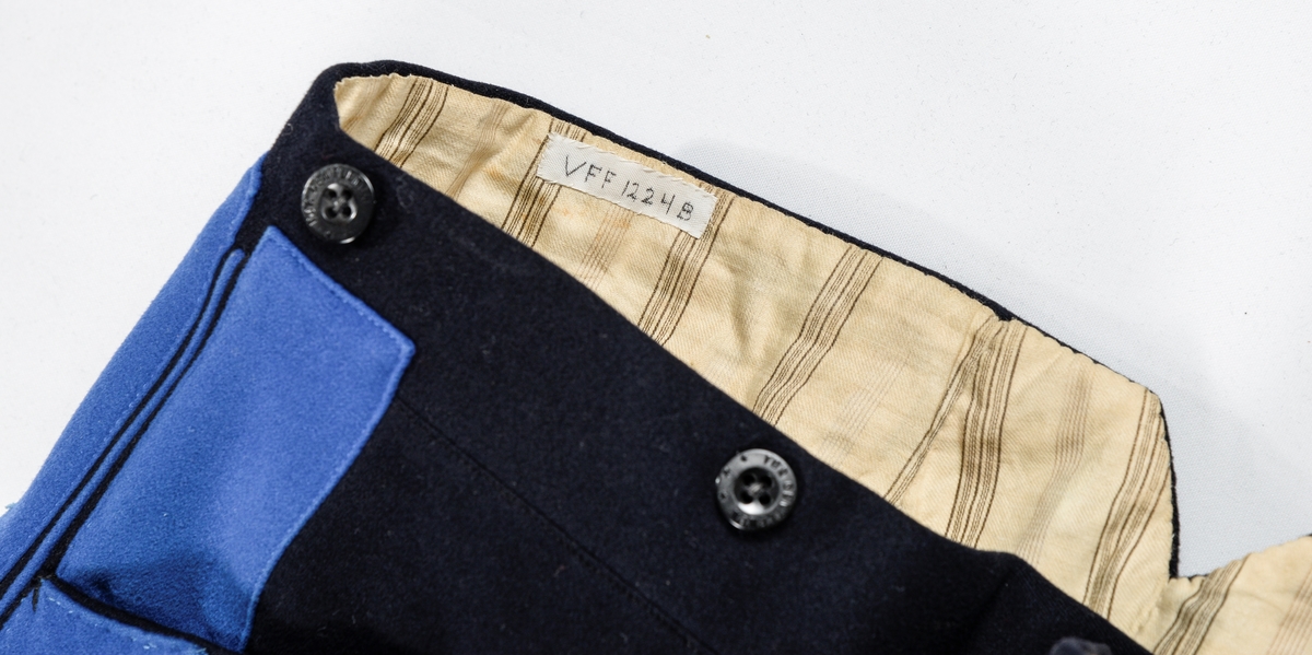 Uniform, løyntnantsuniform, i svart klede med kantar i blått klede. Registreringa inneheld A. Trøye, B Bukse, C Lue, D og E Pålettar. Sjå nærare fyldig registrering på arkivkort frå 1969.