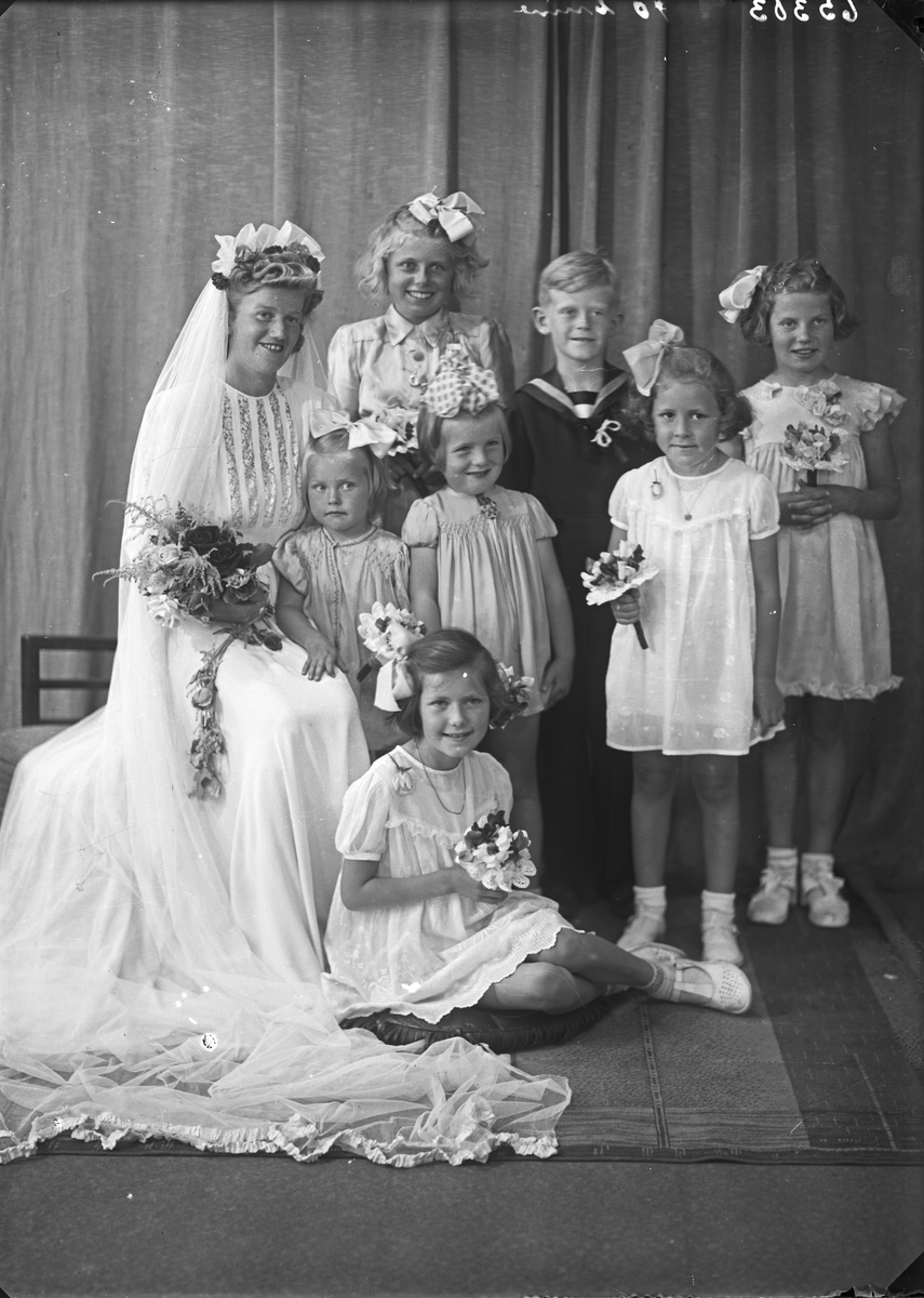 Gruppebilde. Brud med seks unge piker og en ung gutt. Bestillt av Fredrik Jansen. Trygdekassen.