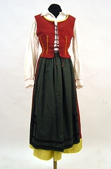 Förkläde sytt av grönt bomullstyg vävt i tuskaft. Nedtill är svarta band applicerade. På linningen är ett blått maskinbroderat band applicerat.

Enl liggare: 100570:1-4  "Västgötadräkt av bomull, bestående av vit blus, rött livstycke, röd kjol samt grönt förkläde."

"Brukats av Lizzie Lindgren som möjligen sytt den på Vara folkhögskola 1922"