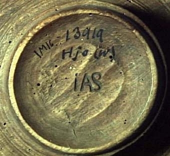 Litet, svarvat fat med 25 mm hög fot. Fatet har dekor i form av bl.a. ristade linjer på ut- och insida. "IAS" är brännstämplat under foten.