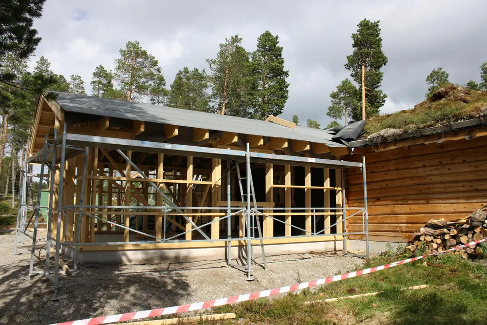 Påbygget på infohuset bygges. Reisverk og tak er bygd. Rundt påbygget står det et stilas.