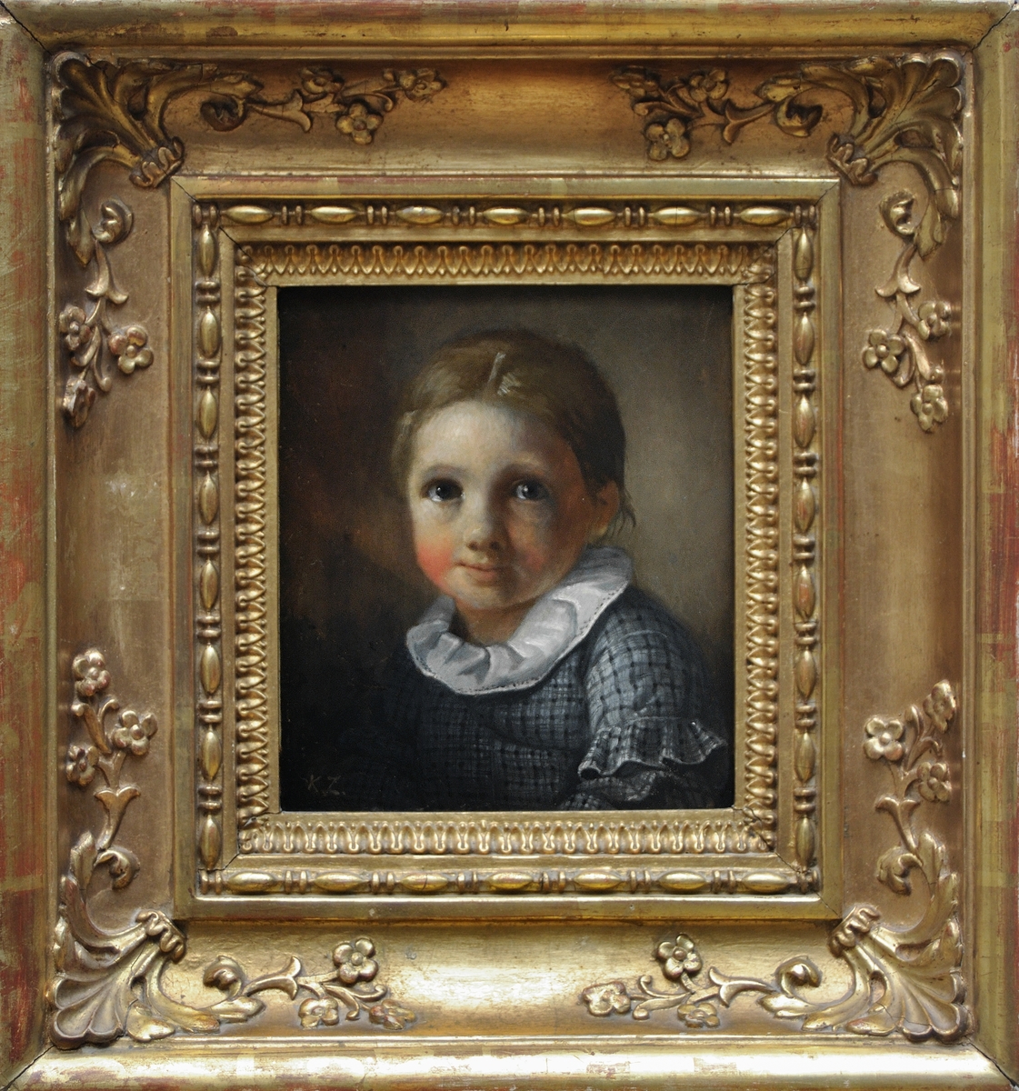 Studie eller porträtt av barn, bröstbild, fas något till höger. Brunt hår, stora blå ögon. Vit rynkad krage och rutig klänning, ärmarna med rysch. Målad omkring 1847. Förgylld ram.