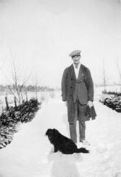Ukjent mann med hund i vinterlandskap.