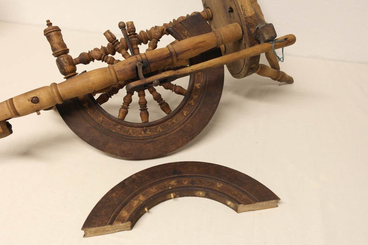 Stående hjulrokk i tre med spinneapparatet plassert over hjulet. Rokken har opprinnelig hatt tre bein.