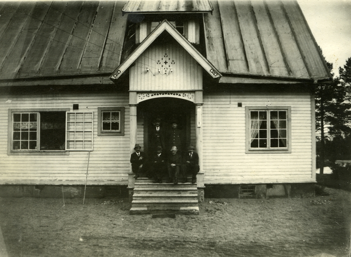 Våningshus i Adolfsnes, Ljørdalen. Fire menn sittende på trappa, to menn stående bak.