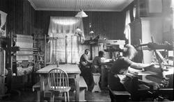 Interiør, bl.a. med vevstoler som brukes av tre uidentifiser