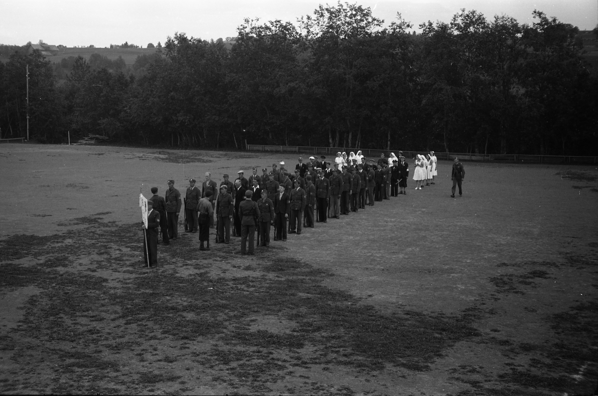 Milorggruppa på Kolbu (HS1432-4), samt lotter, deffilerer på Kolbu Idrettsplass, trolig i forbindelse med et arrangement i anledning Milorgs demobilisering i juli 1945. Åtte bilder.