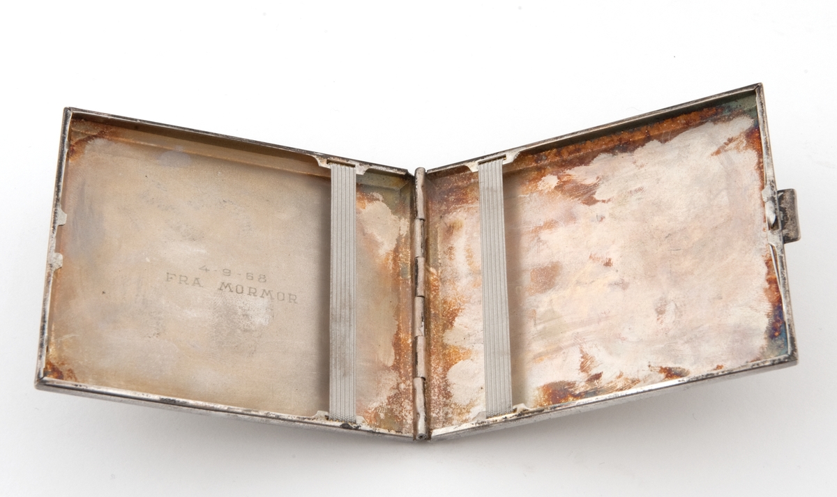 Sigarettetui i nysølv med strikk i bunn og lokk for feste av sigaretter. 