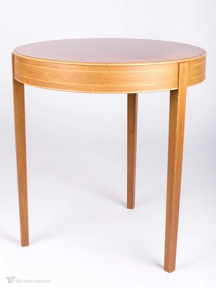 Lavt bord med rund bordplate og rette ben. Finer er satt inn i bordplate og sarg.
